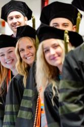 graduates in caps and gowns smiling at camera