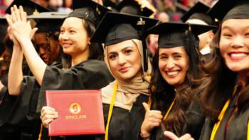 graduates in caps and gowns celebrating with 'sinclair' diploma