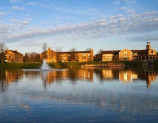 campus buildings reflected in a lake with a fountain