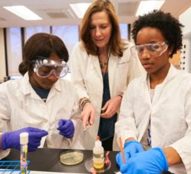 students in lab coats and goggles conducting experiments
