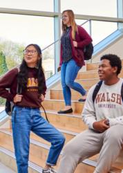 students socializing on a staircase, wearing walsh university apparel