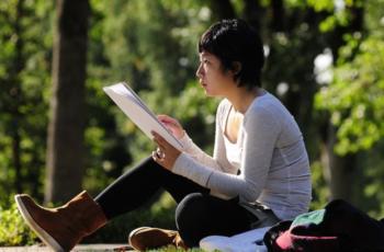 student reading outdoors on a sunny day