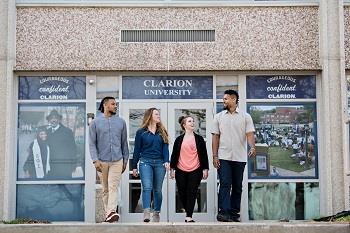 students walking by building with clarion university posters