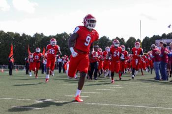 football team entering field led by player #9