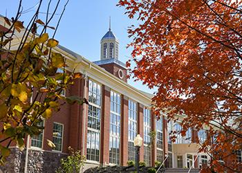 close-up of a campus building framed by autumn leaves