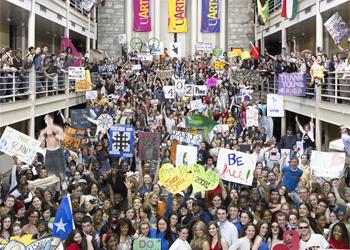 crowded atrium with students holding signs