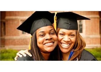 two graduates smiling and hugging