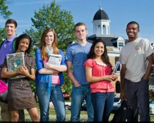 students posing in front of a campus building