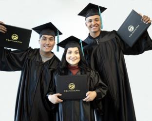 three graduates in caps and gowns holding diplomas