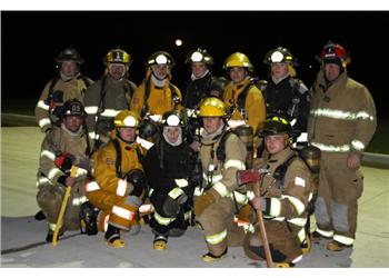 group of firefighters posing for a photo at night