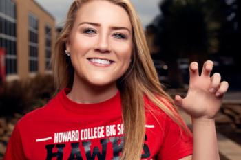 student in red 'howard college big spring hawks' t-shirt smiling and making a claw gesture