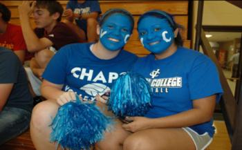 students in blue face paint with pom-poms