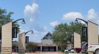 entrance of a campus with flags and a clear sky