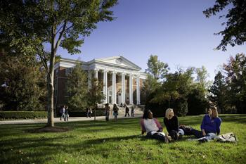students on grass in front of grand building with columns