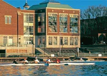 people rowing boats in front of a large building