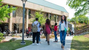 students walking on campus pathway near a modern building