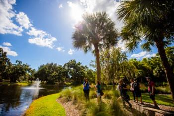 group of students walking by a pond on campus