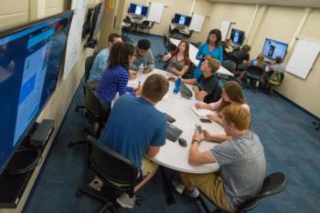 students collaborating around a table with monitors