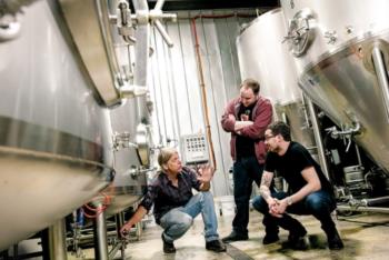 people conversing in a brewery with tanks