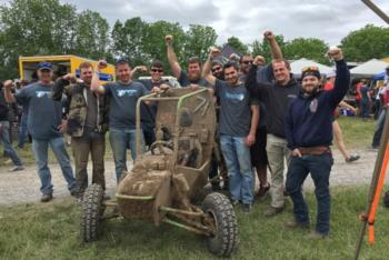 group with muddy vehicle celebrating