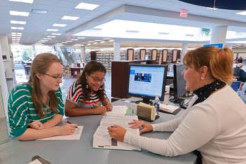 students studying with a tutor in a library