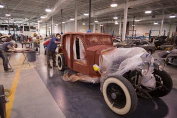 people restoring a vintage car in automotive lab