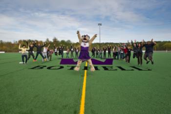 mascot at center of sports field with people jumping