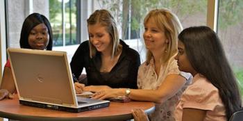 four students around a laptop