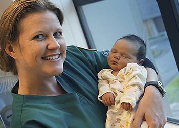 nurse holding a sleeping newborn baby