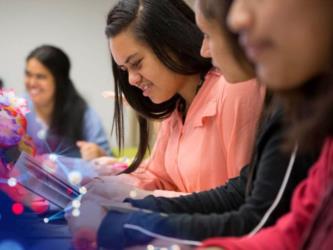 students smiling and using tablets in a classroom setting